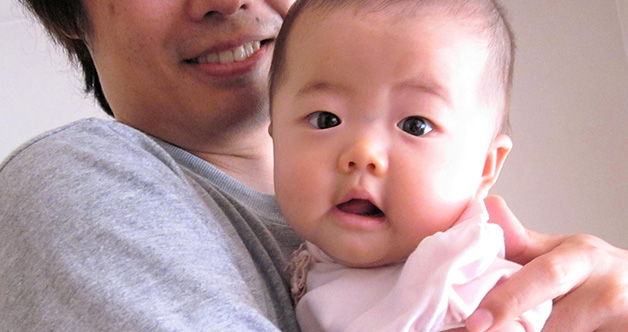 子どもを抱きかかえる男性の写真
